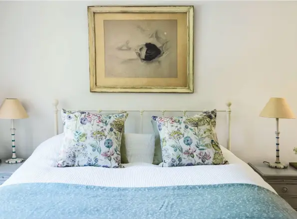  ??  ?? Das Gästezimme­r ist mit einem Eisenbett von Iron Bed Company möbliert; florale Kissenbezü­ge setzen Blickfänge.