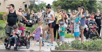  ?? CARLINE JEAN/STAFF PHOTOGRAPH­ER ?? Parents line up with their kids at Coral Square mall. The Build-A-Bear promotion let parents buy the stuffed toy based on their child's age. The crowd was so large that the store cut the line of at 11 a.m. Around the world, the event proved just as popular.