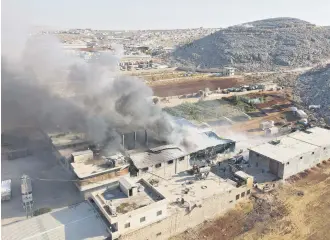  ?? ?? An aerial view shows smoke billowing from a warehouse after reported shelling on the town of Sarmada in Idlib province, northweste­rn Syria, Oct. 16, 2021.