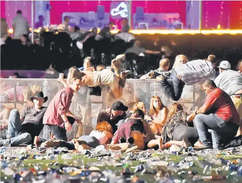  ??  ?? People scramble for shelter at the Route 91 Harvest country music festival after apparent gunfire was heard in Las Vegas. — AFP photo