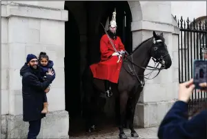  ?? (AP/Alastair Grant) ?? Raajev Thakrar holds his daughter Maya as his wife Anjali takes a photo on her smartphone as he stands next to a member of the Household Cavalry in Horse Guards Parade in London, late last month.
