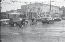  ?? CP PHOTO ?? Cyclists make there way through Toronto during a thundersto­rm.