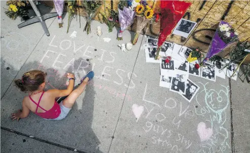  ?? MARK BLINCH / THE CANADIAN PRESS ?? A young girl writes a message on the sidewalk at a site rememberin­g the victims of Sunday’s Toronto shooting.