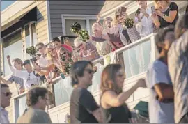  ?? Jay L. Clendenin Los Angeles Times ?? NOT wearing masks and not social distancing, family and friends gather along the Strand in Manhattan Beach to celebrate their graduates from Mira Costa High.