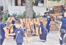  ?? ?? Las tejas están puestas sobre el cordón de cemento de un frondoso árbol de mango donde los estudiante­s corretean.