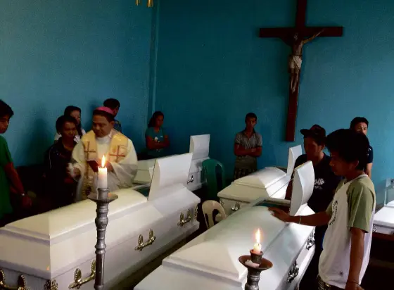  ?? BASILAN Bishop Martin Jumoad visit the remains of several rubber plantation workers slain by the bandit group Abu Sayyaf. Attacks on rubber plantation workers prompted the military to send more troops that triggered a clash yesterday leading to the deaths ??