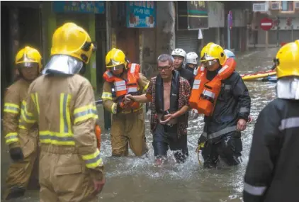  ?? ISAAC LAWRENCE AGENCE FRANCE-PRESSE ?? Un commerçant a été sauvé par des pompiers dans une zone fortement inondée de Macao dimanche.