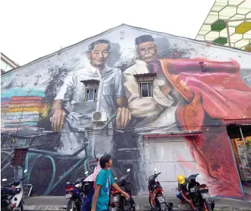  ??  ?? The street art by local mural artist Leornard Siaw featuring fabric entreprene­urs at Indian Street (top) and tinsmiths at China Street (right). These street art are among many in Kuching City which were initiated by DBKU in 2015. — Bernama photos