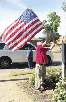  ?? Bill McLoud • Times-Herald ?? Regan Hill puts up a flag at the Forrest City Area Chamber of Commerce. Hill was one of many Lions Club members placing flags around the city in observance of Memorial Day.