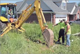  ??  ?? ABOVE: Alan McCarley (from left) runs a backhoe while James Hull and Chris Blackiston show McCarley where to begin excavating.
LEFT: Keelan Freeman with Floyd County Animal Control holds his cellphone down into the excavated area playing kitten...