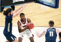  ?? AP Photo/Darron Cummings ?? ■ Arkansas guard Davonte Davis, center, drives to the basket between Oral Roberts guard Kareem Thompson, left, and guard Carlos Jurgens (11) during the second half of a Sweet 16 game in the NCAA men’s basketball tournament Saturday at Bankers Life Fieldhouse in Indianapol­is. Arkansas won, 72-70.