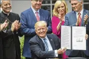  ?? STEPHEN CROWLEY / NEW YORK TIMES ?? President Donald Trump signs an executive order aimed at easing restrictio­ns on political activity by tax-exempt churches during a National Day of Prayer event in the Rose Garden Thursday.