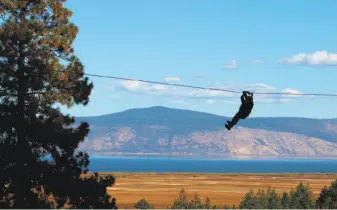  ?? Photos by Jennifer Roe / Special to The Chronicle ?? Chronicle outdoors writer Tom Stienstra hangs by what looks like a thread as he speeds along the zipline over a break in the forest canopy with Klamath Lake in the background.