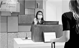  ?? INTERCONTI­NENTAL HOTELS GROUPS ?? A masked front desk agent gestures to a guest at a Holiday Inn Express in Austin, Texas.