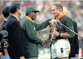  ?? Picture: Ross Kinnaird/Getty Images ?? Nelson Mandela takes his reconcilia­tion project to the heart of white SA as he congratula­tes Bok captain Francois Pienaar on winning the Rugby World Cup in 1995.