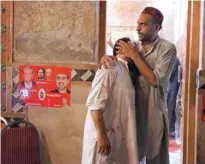  ??  ?? A political party worker comforts another after a suicide attack during an election campaign meeting in Peshawar on Tuesday. — Reuters