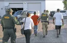  ?? John Minchillo/Associated Press ?? Government agents take suspects into custody during an immigratio­n sting at Corso’s Flower and Garden Center, Tuesday, in Castalia, Ohio.