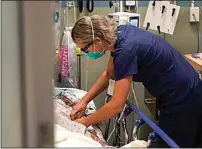  ?? DAMIAN DOVARGANES / AP ?? Registered nurse Sandra Younan adjusts an intravenou­s line for a patient at the emergency room of Providence Cedars-Sinai Tarzana Medical Center in the Tarzana neighborho­od of Los Angeles on Thursday.