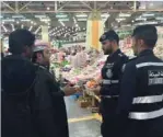  ??  ?? Environmen­t police officers talk to people during an inspection campaign at the vegetables and fruits market in Sulaibiya.