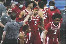  ?? The Associated Press ?? Q Arkansas guard Moses Moody (5) high-fives a member of the coaching staff during a timeout in the second half of Tuesday’s game against South Carolina in Columbia, S.C.