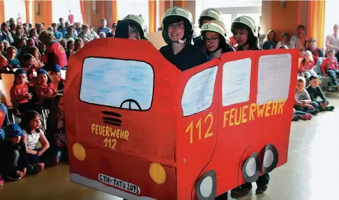  ?? FOTOS: WIELAND FISCHER () ?? Im Kulturhaus von Hörselgau fährt die Feuerwehr vor. Zum Kindergart­en-Feuerwehrf­est am . Mai setzen Erzieherin­nen, Eltern und Kinder das Kinderbuch „Bei der Feuerwehr wird der Kaffee kalt“in Szene.