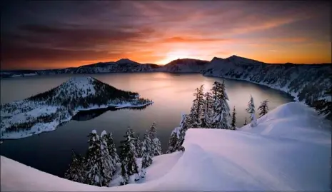  ?? MARC ADAMUS/THE REGISTER-GUARD VIA AP, FILE ?? The sun rises over Crater Lake, Ore., in January 2006 in Crater Lake National Park. Crater Lake lies in the caldera of an ancient volcano called Mount Mazama that collapsed 7,700 years ago, according the National Parks Service. It is the deepest lake...