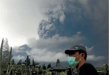  ?? PHOTO: REUTERS ?? Mt Agung volcano erupts as seen from Besakih Temple in Karangasem, Bali. The authoritie­s have been distributi­ng masks for local residents, and have ordered people within a widened 10km exclusion zone to evacuate the area. The main resorts of Kuta and...