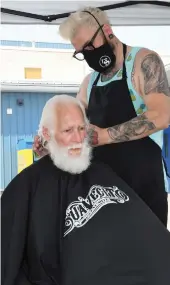  ??  ?? Barber Jason Gauthier works on the shaggy mane of Nick Lyon during the StreetCuts Barber outreach initiative on July 12 in the Sarcan parking lot. Lyon is a regular client but had not visited Gauthier since November due to health problems. Photo by Jason G. Antonio