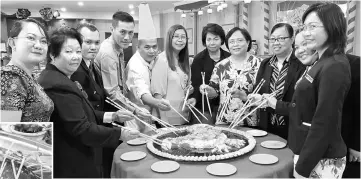  ??  ?? Chef Koad (fifth left), hotel manager Klement Chiam (fourth left) and staff get ready to toss Rainbow Yee Sang. The Golden Pomfret with Assam Curry Sauce ( top) and (bottom from left) Fortune Salted Prawns with Spring Onion, Long Life Noodle with Seafood Egg Sauce and Chicken, and Chilled Natta De Coco with Almond Beancurd.