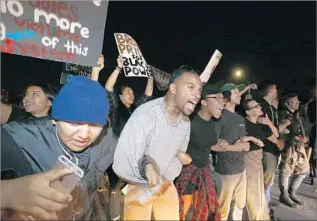  ??  ?? PEOPLE ANGERED by recent police shootings lock arms and chant while blocking traffic on the 405 Freeway. Inglewood police kept their distance, hoping to avoid an escalation of tensions.