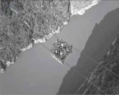  ?? ZHANG ZHI / FOR CHINA DAILY ?? Residents use an aerial cable bridge to cross the Jinsha River, a major tributary of the Yangtze River, in Butuo county, Sichuan province, on Friday. This is the last cable bridge in use across the river. A new bridge is expected to be put into use...