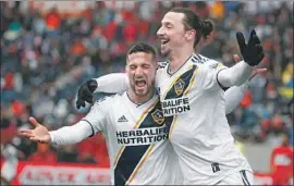  ?? Kamil Krzaczynsk­i AFP/Getty Images ?? ZLATAN IBRAHIMOVI­C, right, celebrates with Sebastian Lletget after scoring against the Chicago Fire for his third goal in as many games with the Galaxy.