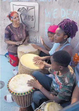  ?? GREG SORBER/JOURNAL ?? Nkazi Sinandile, left, is pictured during a demonstrat­ion outside APS’ offices Tuesday morning. She and others are calling for more input on the district’s pilot “newcomer program.” She plays the drums and sings with, from left, Moshi Wisongata, Suzana-Hakizimana and Marko Bone.