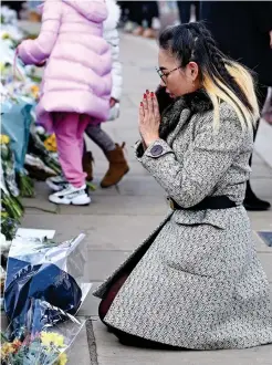  ??  ?? Solemn: A woman kneels in prayer outside the Palace