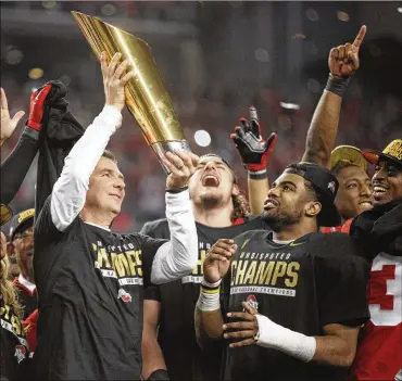  ?? DAVID JABLONSKI / STAFF ?? Ohio State coach Urban Meyer hoists the national championsh­ip trophy as Joey Bosa (back center), Ezekiel Elliott and Tyvis Powel (far right) look on Jan. 12, 2015, at AT&amp;T Stadium in Arlington, Texas.