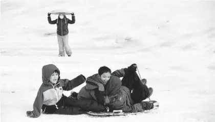  ?? BRIAN KRISTA/BALTIMORE SUN MEDIA ?? Josiah Sierra, left, and his friends Michael and Joshua McDonald enjoy a sled ride down a snowy hill near Longfellow Elementary in Columbia on Feb. 2.