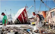  ?? Douglas R. Clifford/Tribune News Service ?? Fleet official Scott Wilson, left, and shrimper Steven Maxey walk by wreckage at Fort Myers Beach, Fla.