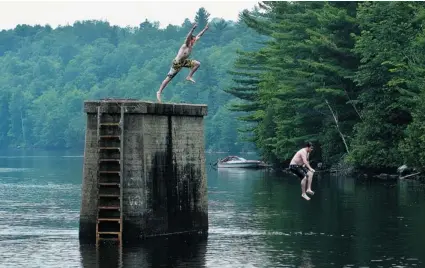  ?? BRUCE DEACHMAN/OTTAWA CITIZEN ?? Alex Adams and Josh Raeside leap off an old bridge support into the Madawaska River at Burnstown, near Renfrew.