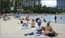  ?? CALEB JONES — THE ASSOCIATED PRESS ?? Brett Walsh and Emma Yates, bottom right, tourists from Australia, sit on Waikiki Beach in Honolulu on Monday to enjoy the Hawaiian sand, surf and sun with others.