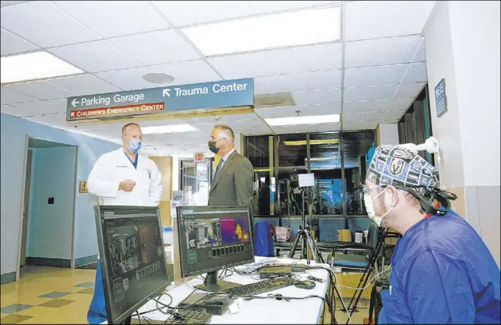  ?? University Medical Center ?? University Medical Center CEO Mason VanHouweli­ng, center, discusses patient volume with UMC Chief of Trauma Dr. Douglas Fraser, left, on Friday.