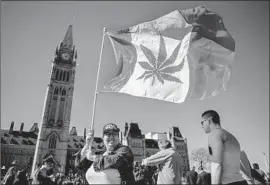  ?? Chris Roussakis AFP/Getty Images ?? THE MAPLE leaf flag gets a marijuana makeover for a demonstrat­ion in Ottawa in 2016. Canada will become the second country to make pot legal nationwide.