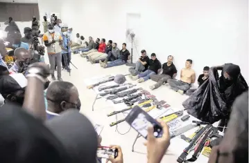  ?? ODELYN JOSEPH Associated Press ?? In this July 8, 2021, photo at police headquarte­rs in Port-au-Prince, suspects in the assassinat­ion of Haiti’s president, Jovenel Moïse, are shown to the media, along with the weapons and equipment they allegedly used in the attack.