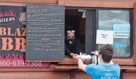  ??  ?? Angelina Gardner, above, of Uncle D’s Blazin’ BBQ, hands a customer his food during the lunch hour at the new Food Trucks on Colman Street in New London. Robert Currier and his son Brody, 9,