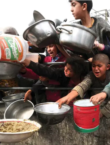  ?? Reuters; AFP ?? Clockwise from top, Palestinia­n children wait for food outside a charity kitchen in Rafah, southern Gaza; Israeli troops survey the rubble from a building in the enclave; smoke rises after air strikes in Khan Younis yesterday