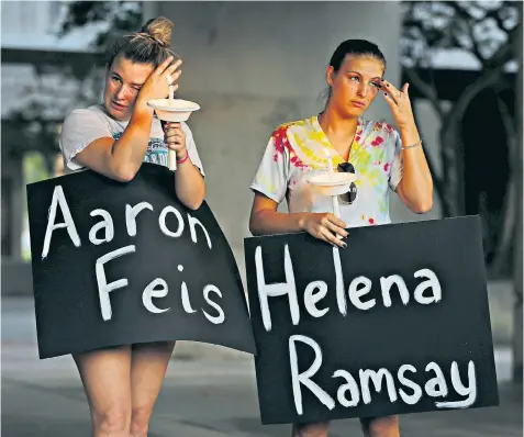  ??  ?? Parkland residents Tori Stetzer and Taylor Miller hold placards featuring the names of school shooting victims during a candle-lit vigil in Florida