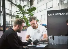  ?? — AFP ?? Chipsters: Osterlund (right) implanting a chip into a man during a chip implant event in Epicentre, a technologi­cal hub in Stockholm.