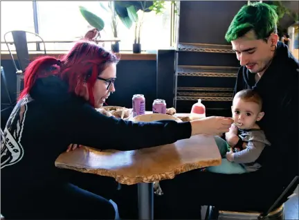  ?? DANIELLE RAY — SENTINEL & ENTEPRISE ?? Leominster residents Kyle Cawley and Megan Hardy’s adorable 10-month-old daughter Penelope enjoyed some mashed potatoes from her parents’ lunch bowls at the Valentine’s Day Roots cafe reopening.