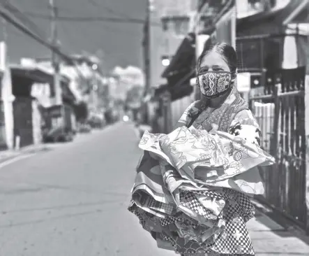  ?? BERNARD TESTA ?? JENNIFER NABAUNAG, 37, from Muzon, Taytay, Rizal, sells bedsheets and pillow cases by consignmen­t, literally carrying, on foot, an average of around 20 kilos of her items in Rizal towns, hoping to slowly regain what she used to earn pre-pandemic. Although she got P6,500 in government aid, the lockdowns have left her with only a net of P300 daily, not enough to buy her household’s food and other items, but she bears her burden, as she’s also saving up to buy even just a used tablet for her 16-year-old son’s virtual schooling. She hopes that as Christmas nears, more people will buy her stuff.