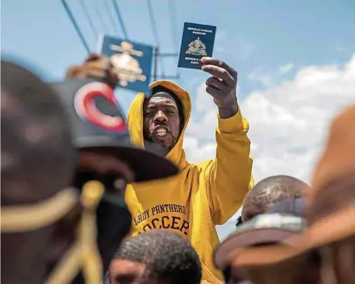  ?? Foto: AFP ?? Vor der US-Botschaft in Tabarre zeigen aufgebrach­te Haitianer ihre Pässe und bitten um Asyl.