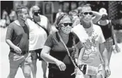  ?? JOHN RAOUX/AP ?? Guests wear masks in the summer sun while visiting the Disney Springs complex June 16 in Lake Buena Vista.